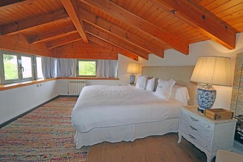 a bedroom with a large white bed and wooden ceilings at Hotel El Babú in Caravia