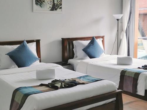 a bedroom with two beds with white sheets and blue pillows at Sasimanta in Kamala Beach