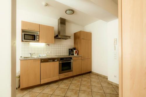a kitchen with wooden cabinets and a stove top oven at Panorama Spa Lodges DAS.SCHILLER in Bad Gastein