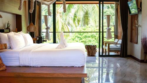 a bedroom with a bed and a large window at Long Beach Chalet - SHA Extra Plus in Ko Lanta