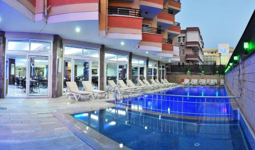 una grande piscina con sedie in un edificio di KLEOPATRA SUNLIGHT HOTEL a Alanya