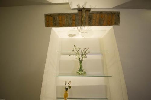 a shelf with a vase with flowers in it at Residenza il Gelsomino in Cantello