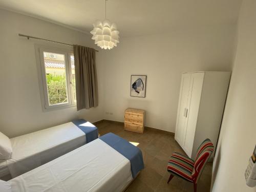- une chambre avec deux lits, une chaise et un lustre dans l'établissement Villa Cossyra, à Porto Palo