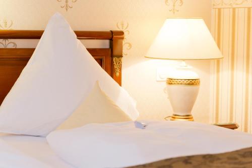 a bed with a white pillow and a lamp at Hotel Villa Monte Vino in Potsdam