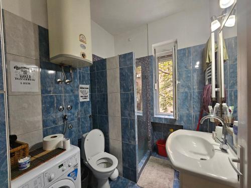 a blue and white bathroom with a toilet and a sink at The Traveling Theater in Belgrade