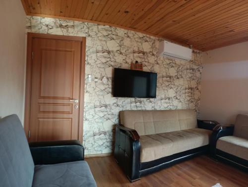 a living room with a couch and a tv on a stone wall at Villa Pamuklu second floor only in Çaykara