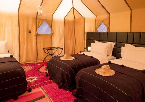 two beds in a tent with hats on them at Sahara Relax Camps in Zagora