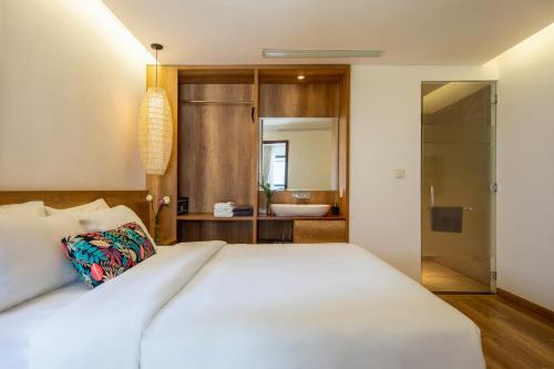 a bedroom with a white bed and a bathroom at K House Apartment Danang Beach in Da Nang