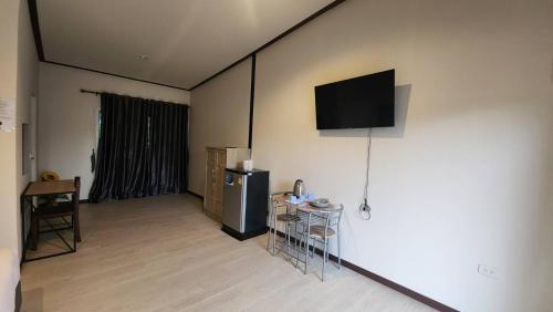 Cette chambre dispose d'un réfrigérateur et d'une télévision murale. dans l'établissement Riverhill khaoyai บ้านกล่อง, à Ban Bung Toei