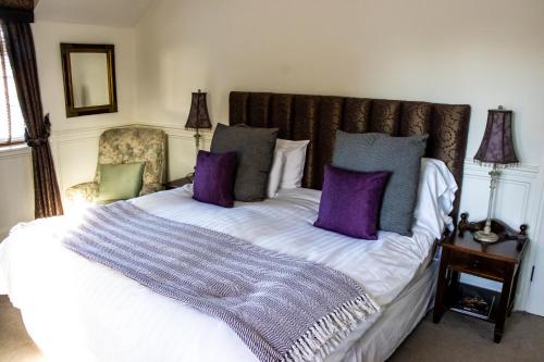 Una cama con almohadas moradas y grises. en The Lord Bute en Highcliffe