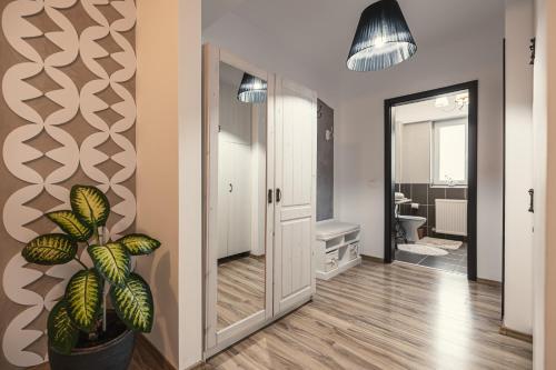 einen Flur mit Spiegel und Topfpflanze in der Unterkunft Olivia's Home in Sibiu