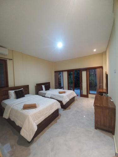 two beds in a large room with windows at Agung Trisna Bungalows in Ubud