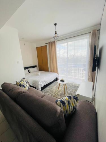 a bedroom with a couch and a bed and a window at One Bedrooms & Studios at Ngong Rd in Nairobi