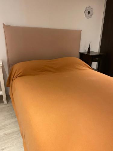 Una cama con una manta naranja encima. en Departamentos Avi en Tigre
