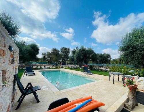 een zwembad in een achtertuin met stoelen en een tafel bij All'ombra degli Ulivi by BarbarHouse in Latiano