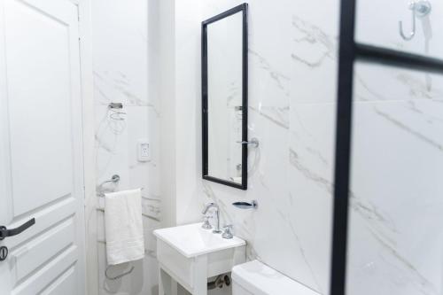 Baño blanco con lavabo y espejo en RG Hotel Boutique en Chivilcoy