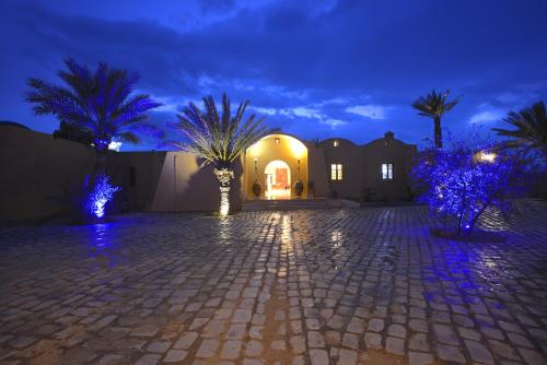 a house with palm trees and lights in a driveway at Dar Almassa in Mellita