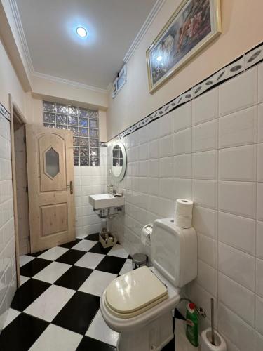 a bathroom with a toilet and a checkered floor at Residência Mendonça in Faial