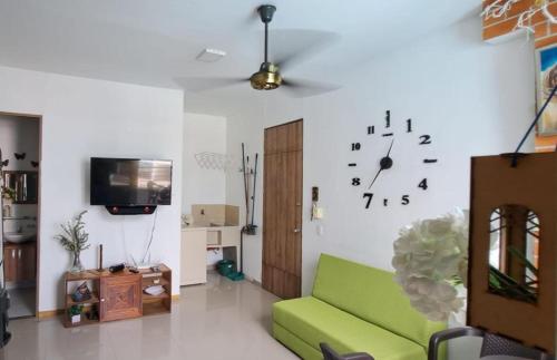 uma sala de estar com um sofá verde e um relógio na parede em Condominio Paraíso del Sol em San Jerónimo