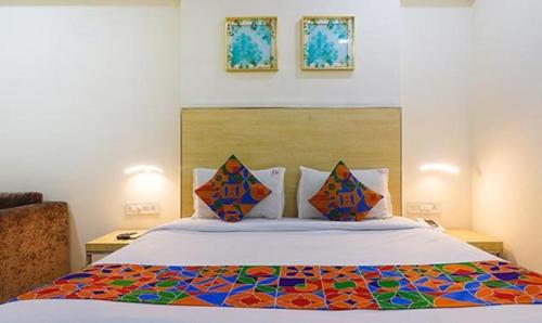 a bedroom with a king sized bed with a colorful comforter at FabHotel Swarnas in Vijayawāda