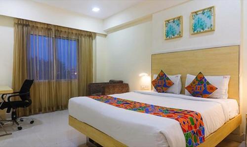 a bedroom with a bed and a desk and a window at FabHotel Swarnas in Vijayawāda