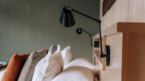 a bedroom with a bed with white pillows and a lamp at Andeluna Winery Lodge in Tupungato