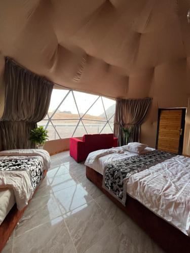 two beds in a room with a large window at Sandy Camp Wadi Rum in Wadi Rum