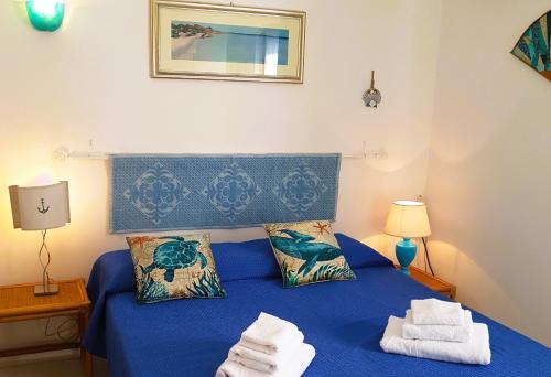 a bedroom with a blue bed with towels on it at Rosa dei venti in Stintino