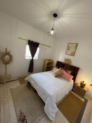 una camera da letto con un letto con lenzuola bianche e cuscini rosa di K11SURF ad Aourir