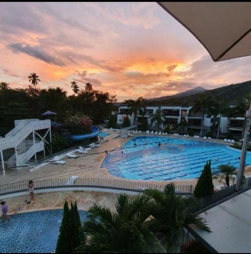 a large swimming pool with a sunset in the background at Apartasol Santafe de Antioquia in Santa Fe de Antioquia