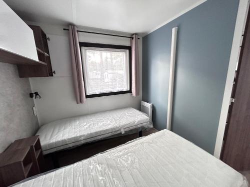 ラ・パルミールにあるMobil home de 44m2のベッド2台と窓が備わる小さな客室です。