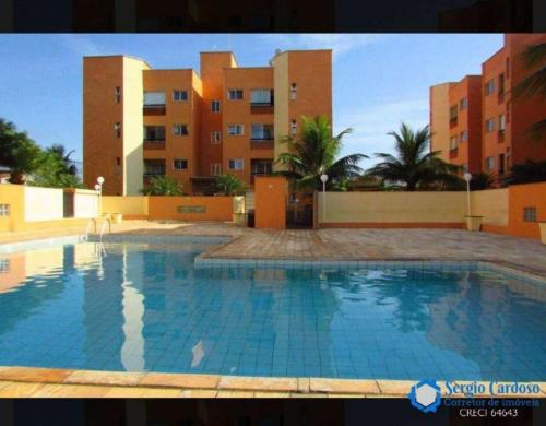 uma grande piscina em frente a alguns edifícios em Apartamento em Itanhaém com 2 quartos, Piscina e Ampla Varanda Gourmet em Itanhaém