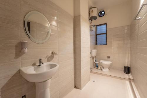 a bathroom with a sink and a mirror and a toilet at Alhanney Housing in Guwahati