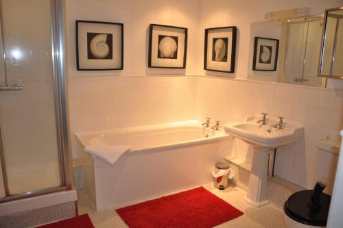 a bathroom with a bath tub and a sink at Spacious Thatched Cottage in West Lulworth, Dorset in West Lulworth