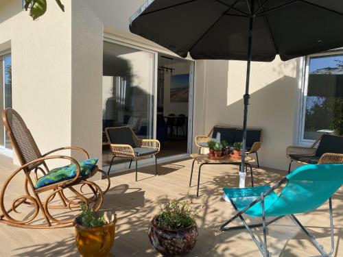 une terrasse avec des chaises et un parasol dans l'établissement Alice’s house, Maison & Grange à 10km de l’Océan, à Naujac-sur-Mer