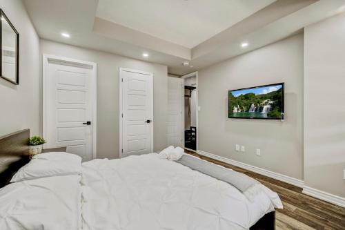 a bedroom with a white bed and a tv on the wall at Modern Family Friendly 4BR Home Away From Home in Milton