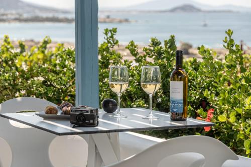 a table with two glasses of wine and a camera at Lianos Village in Agios Prokopios