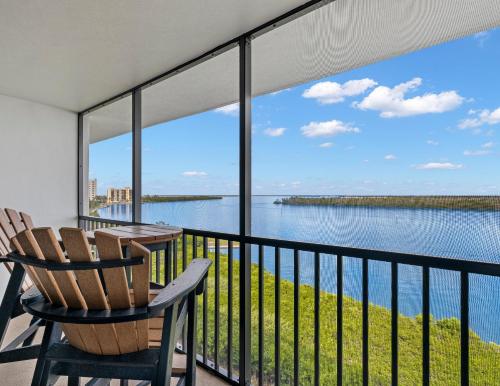 フォートマイヤーズビーチにあるPalms of Bay Beach 4Fの椅子2脚と水辺の景色が見えるバルコニー