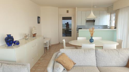 a living room and kitchen with a couch and a table at Zeemeermin in Nieuwpoort