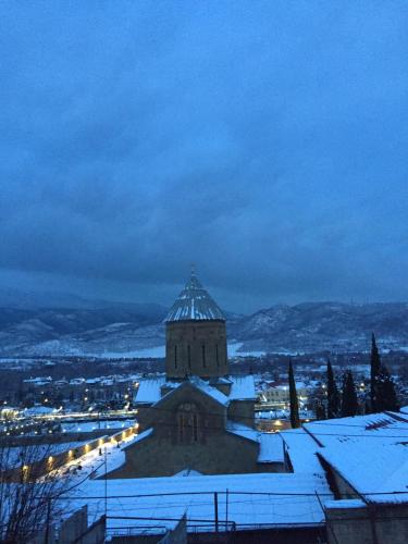 a building with snow on the roof at night at garden and panorama in Mtskheta