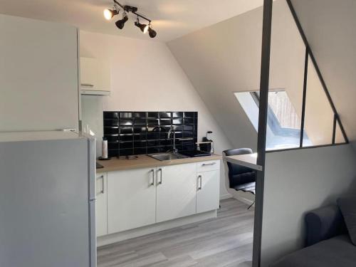 una cocina con armarios blancos y una escalera en un loft en Magnifique studio de charme, en Évreux