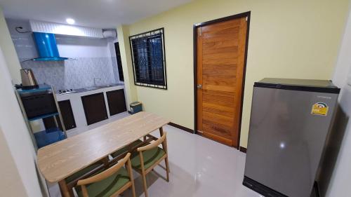 a small kitchen with a wooden table and a refrigerator at Hatyai.Muslim.Home in Hat Yai
