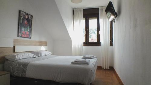 1 dormitorio con 1 cama con sábanas blancas y ventana en MR, en Villaviciosa