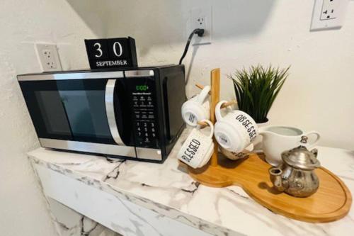 a microwave sitting on top of a counter with mugs at Charming 2-Room Oasis - Miami in Tamiami