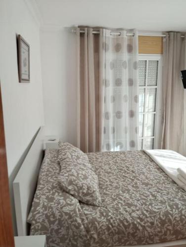 1 cama en un dormitorio con cortina y ventana en Piso encantador Mediterráneo, en Rincón de la Victoria