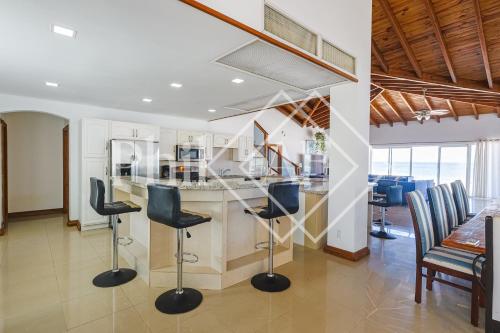 a kitchen with a bar with chairs and a table at 10 bed-rooms luxury BEACH VILLA in Guana Bay