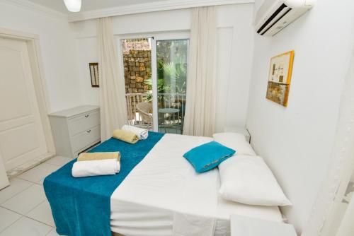 een slaapkamer met een groot wit bed met blauwe accenten bij The Royal Links two bedroom apartment in Ortaca