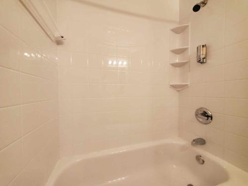 y baño de azulejos blancos con bañera blanca. en Hôtel le 625 en La Malbaie
