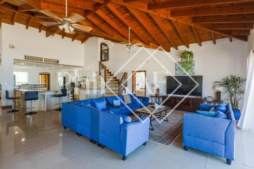 a living room with blue couches and a kitchen at 10 bed-rooms luxury BEACH VILLA in Guana Bay