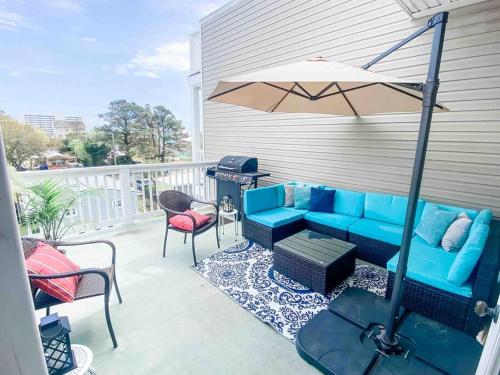 a patio with a blue couch and an umbrella at Luxury Townhouse w/ Golf Cart & Private Elevator in Carolina Beach